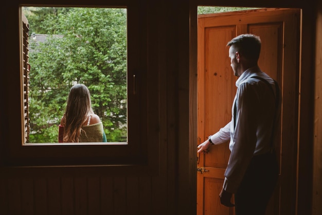 Le marié ouvre la porte du balcon du cottage où la mariée l'attend