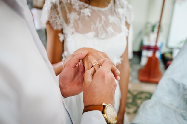 Le marié porte une bague de fiançailles en or au doigt de la jolie mariée Cérémonie de mariage