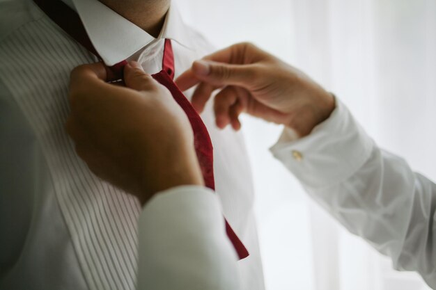 Le marié redresse le nœud papillon. Homme redressant son nœud papillon rouge. Se préparer. mariage