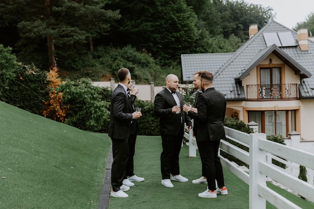 marié et ses amis garçons d'honneur en costumes élégants buvant du whisky en plein air