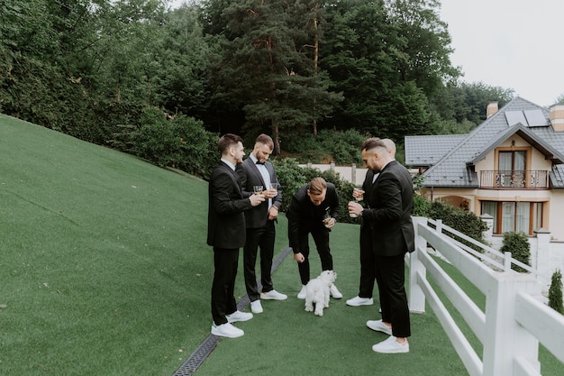 marié et ses amis garçons d'honneur en costumes élégants buvant du whisky en plein air