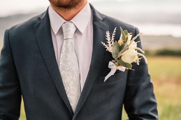 Le marié en smoking noir et noeud papillon corrige ses boutons sur une chemise blanche