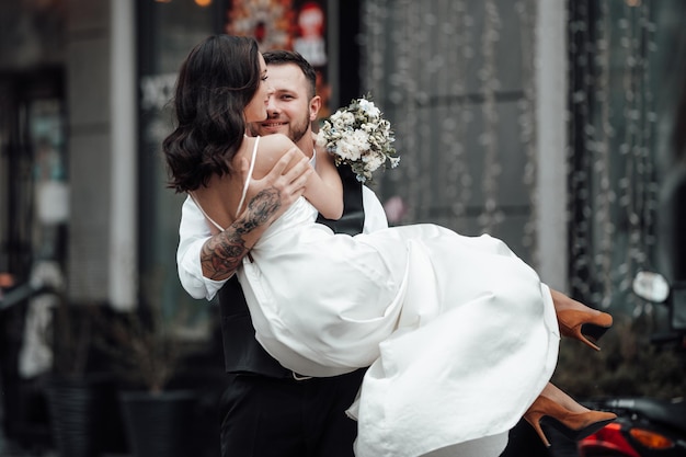 Photo le marié soulève la mariée alors qu'il se tient à l'extérieur