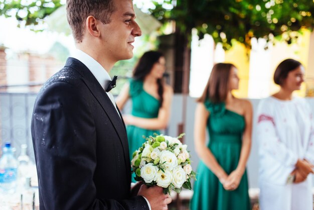 Le marié tient un bouquet de mariée