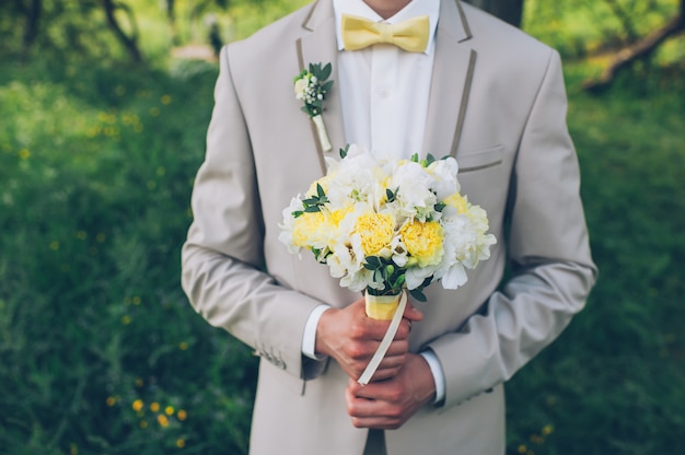 Le marié tient un bouquet de mariée