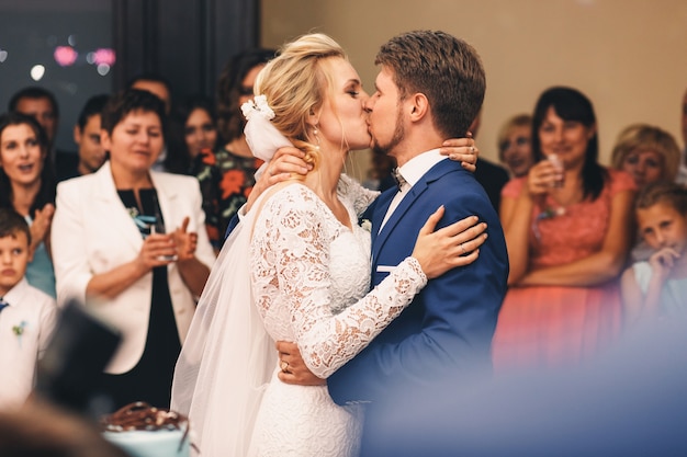 Le marié tient la mariée étroitement pendant qu&#39;ils s&#39;embrassent dans la foule des invités