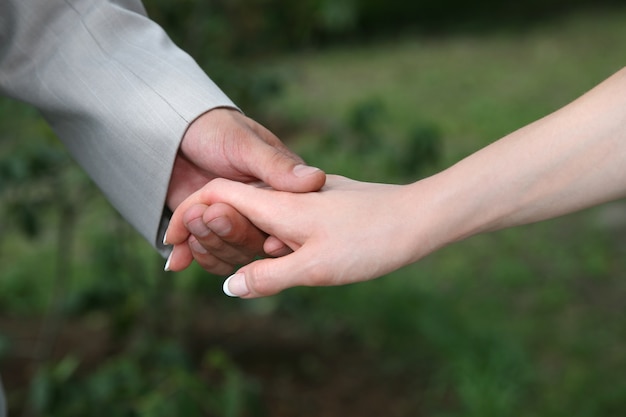 Le marié tient la mariée par la main gros plan