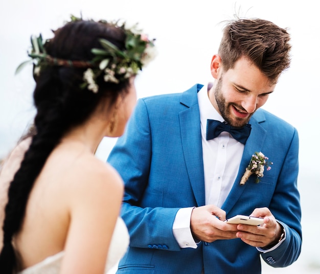 Marié vérifiant son téléphone à la cérémonie de mariage de plage