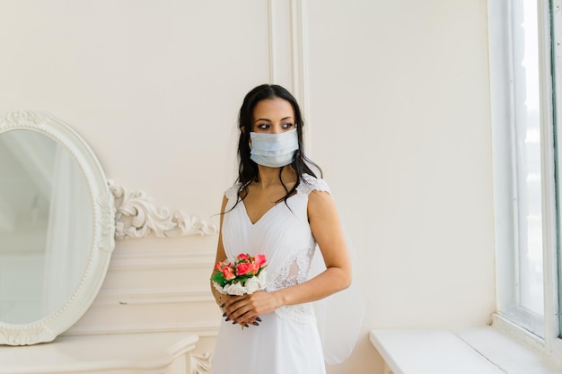 Mariée afro-américaine en masque vestimentaire et le matin se préparant pour le mariage dans la chambre d'hôtel