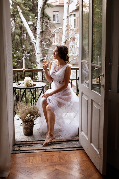 Photo mariée sur le balcon avec verre de champagne