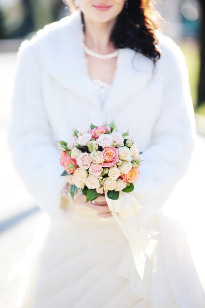 La mariée avec un beau bouquet de mariée de roses.