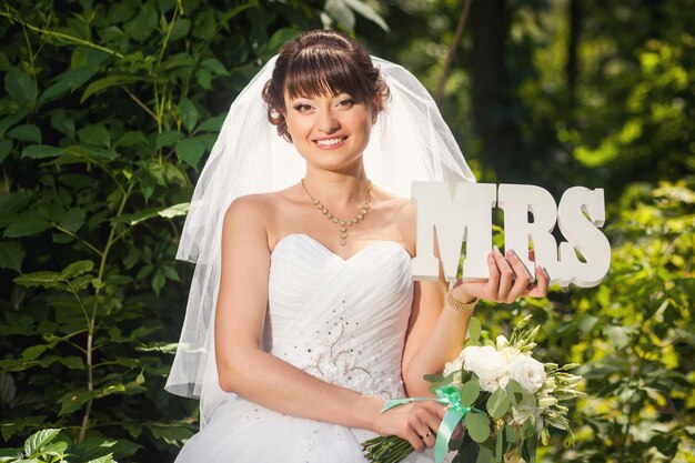 Mariée de beauté dans la forêt d'été avec signe MRS