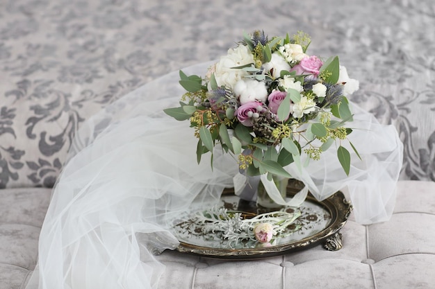 Mariée en belle robe assise sur un canapé à l'intérieur dans un intérieur de studio blanc comme à la maison Style de mariage à la mode tourné en pleine longueur