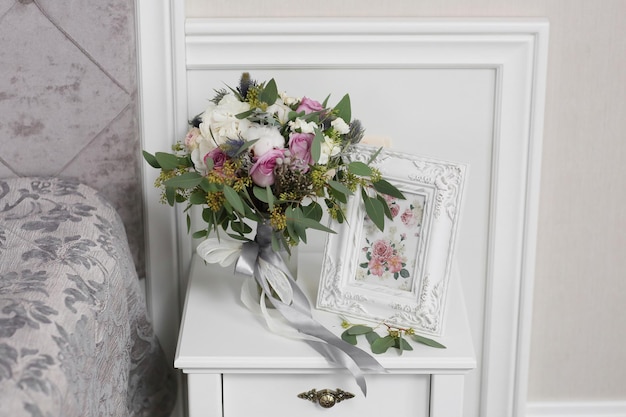 Mariée en belle robe assise sur un canapé à l'intérieur dans un intérieur de studio blanc comme à la maison Style de mariage à la mode tourné en pleine longueur