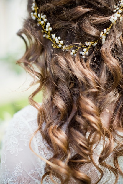 Mariée bouclée avec une belle coiffure et des accessoires dorés dans les cheveux en plein air