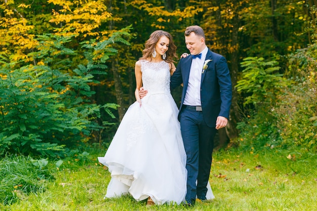 Mariée bouclée élégante et marié élégant marchant dans le beau parc d'été