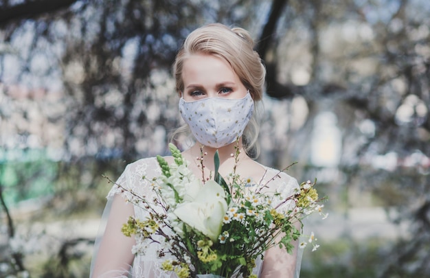 Mariée avec un bouquet dans un masque de protection