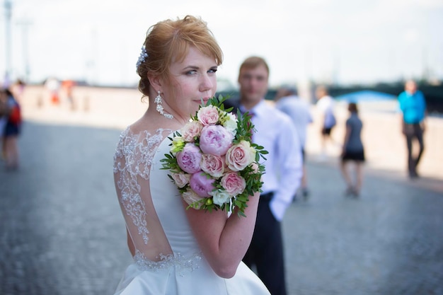 Mariée avec un bouquet dans une robe blanche sur fond de marié