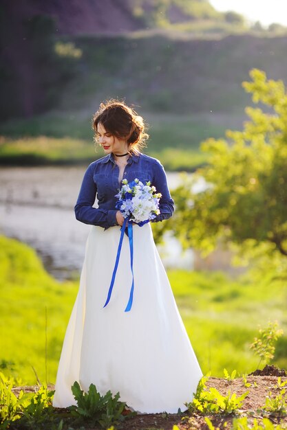 Mariée avec un bouquet de mariée au coucher du soleil