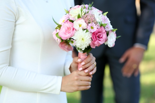 Mariée avec bouquet de mariée et marié sur fond de nature