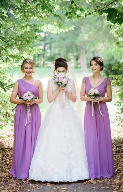 La mariée cache son visage derrière le bouquet de mariée posant avec ses demoiselles d&#39;honneur