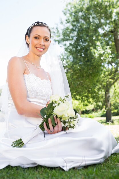 Photo mariée confiante tenant le bouquet dans le jardin