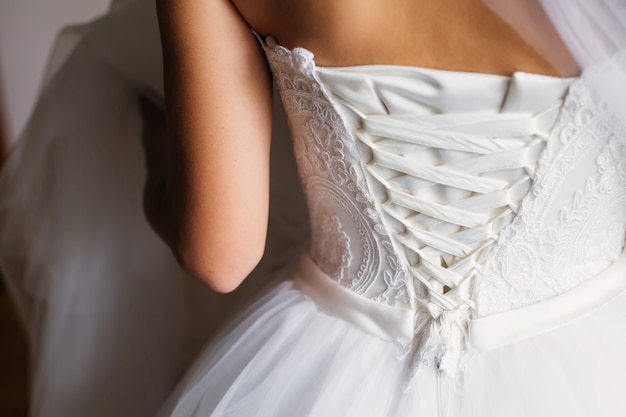 La mariée dans une belle robe blanche et un corset avec un ruban.