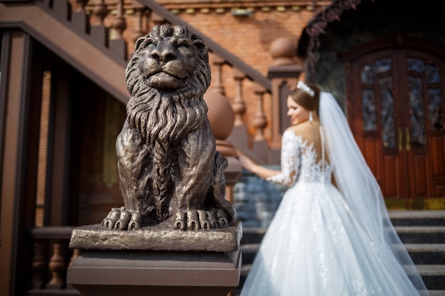 Mariée dans une belle robe blanche et longue sur fond d'un immeuble en brique