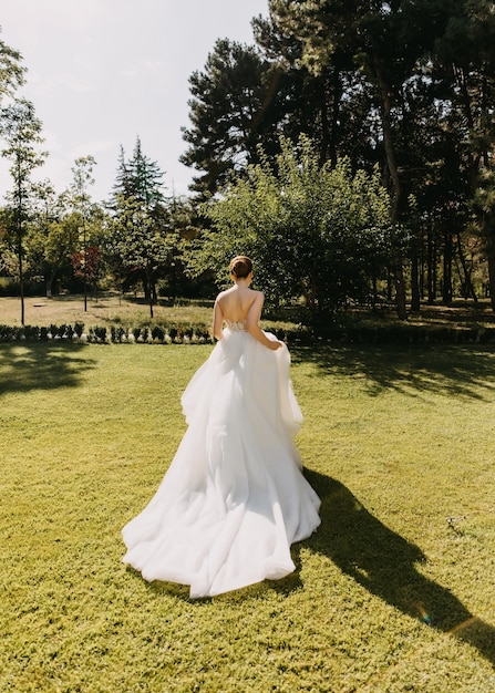 Mariée dans une longue robe blanche s'enfuyant sur l'herbe verte