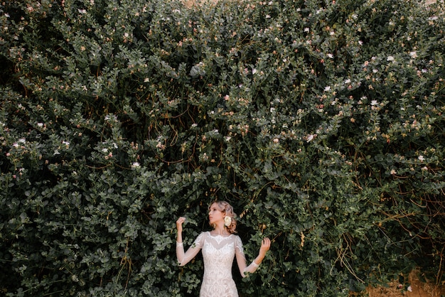 Une mariée dans une robe blanche avec un bouquet de fleurs dans ses mains pose
