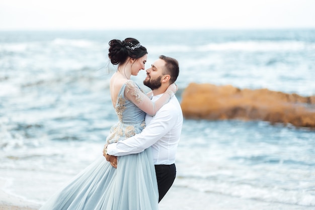 mariée dans une robe bleue marche le long du rivage de l'océan