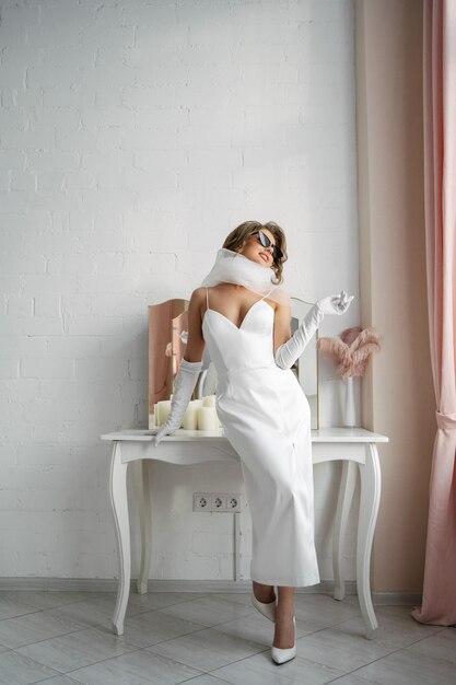 Photo mariée dans une robe élégante avec des lunettes de soleil dans un intérieur lumineux