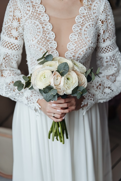 Une mariée dans une robe de mariée de style bohème tient un bouquet de fleurs délicates.