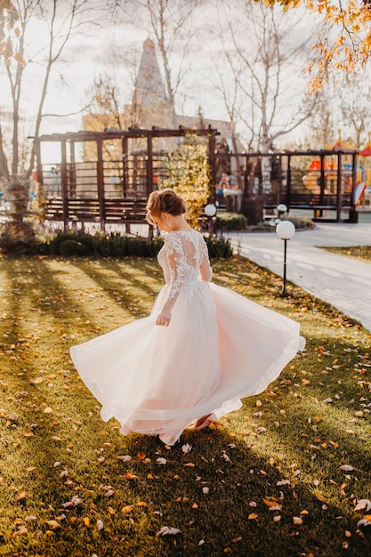 La mariée danse dans une magnifique robe dans le parc.
