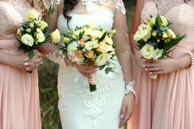 Mariée et demoiselles d'honneur tenant des bouquets de mariage sur leurs mains