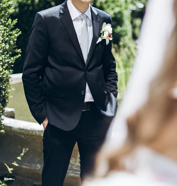 Mariée élégante avec bouquet de pivoine et marié en costume posant dans un jardin ensoleillé le jour du mariage couple de mariage de luxe heureux jeunes mariés famille moments romantiques