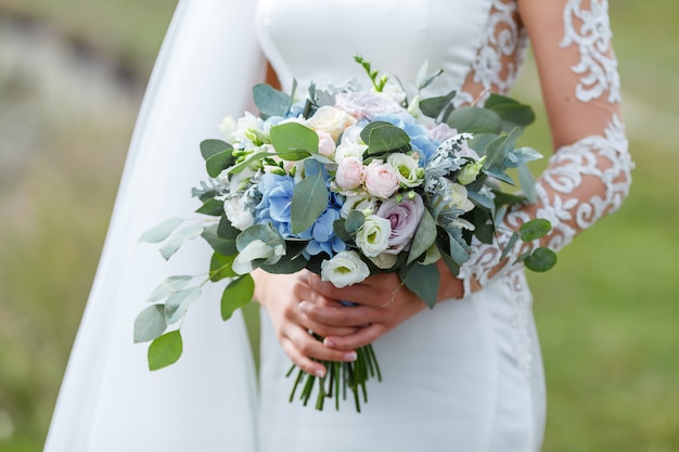 Mariée élégante dans une robe de mariée avec dentelle tenant un bouquet de fleurs de mariée