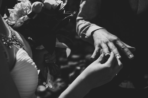 La mariée élégante porte une bague en or sur la main du marié.