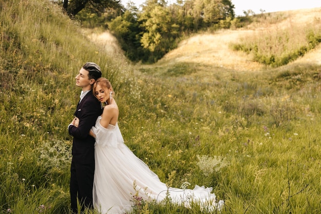 Photo la mariée embrasse un beau marié élégant beau couple dans la nature sur fond de collines