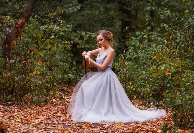 mariée est assise dans la forêt d'été. modèle dans une forêt de fées. promenade d'été. Belle robe de mariée violette.
