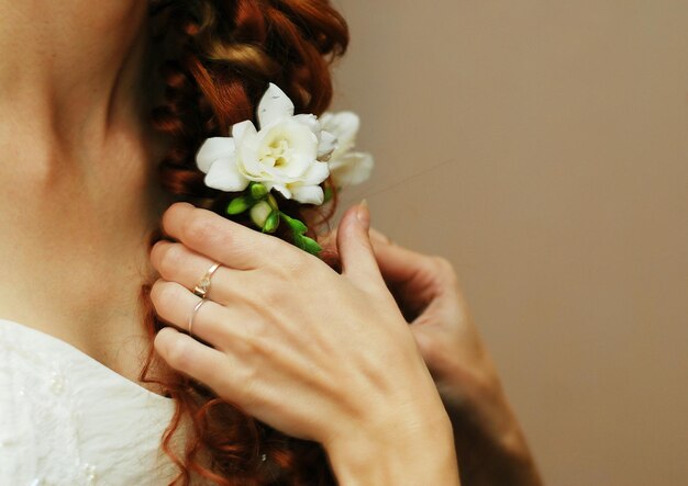 La mariée est tressée et décorée de fleurs de freesia blanches