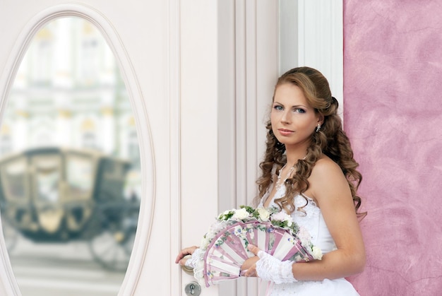 Mariée avec fanbouquet de mariage près du miroir