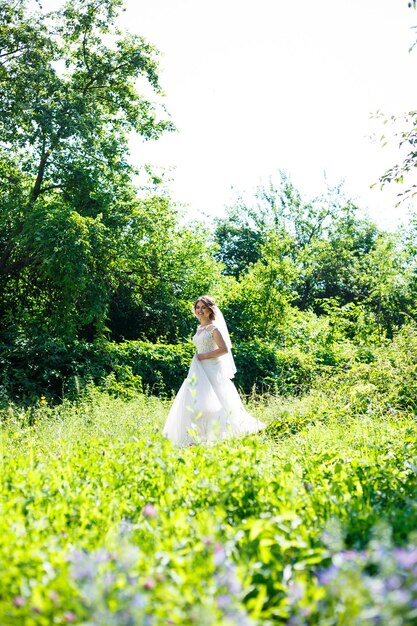 Mariée De Fille Heureuse Dans Une Longue Robe De Mariée Blanche Et Dans Un Tourbillon De Voile Dans Un Parc Verdoyant Sur La Nature.