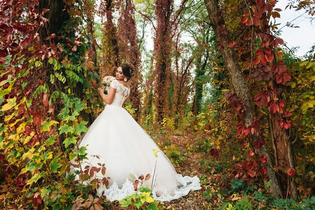 Mariée sur fond d'arbres colorés dans le parc d'automne