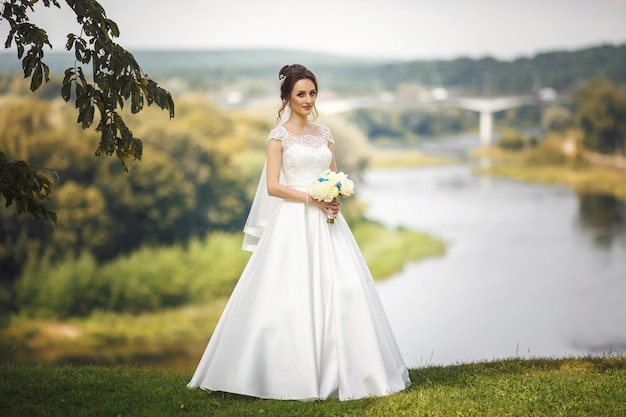 La mariée sur une haute falaise près de la rivière Promenade des jeunes mariés Le jour du mariage Le plus beau jour d'une jeune femme