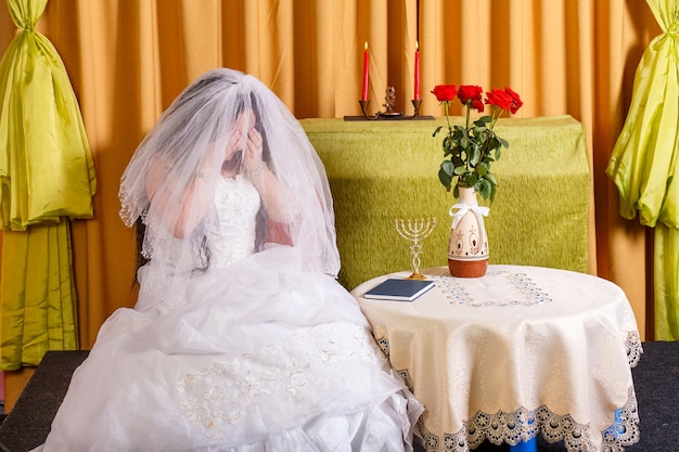 Mariée juive dans une robe blanche luxuriante, le visage couvert d'un voile, pleurant avant la cérémonie chupa ne veut pas se marier