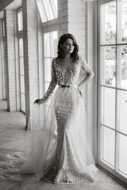 Une Mariée Luxueuse Dans Une Robe De Mariée Le Matin Dans Son Intérieur. Photo Noir Et Blanc.