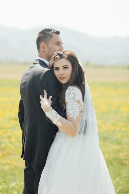 Mariée et le marié au jour du mariage marchant à l'extérieur sur la nature verte d'été.