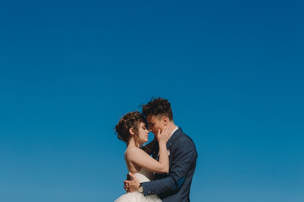 Photo mariée et le marié câlins sur la jetée contre le ciel