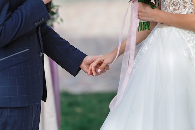 mariée et le marié sur la cérémonie de mariage. jeunes mariés heureux, main dans la main à l'extérieur se bouchent. concept de mariage. Jour de mariage. Beau couple juste marié